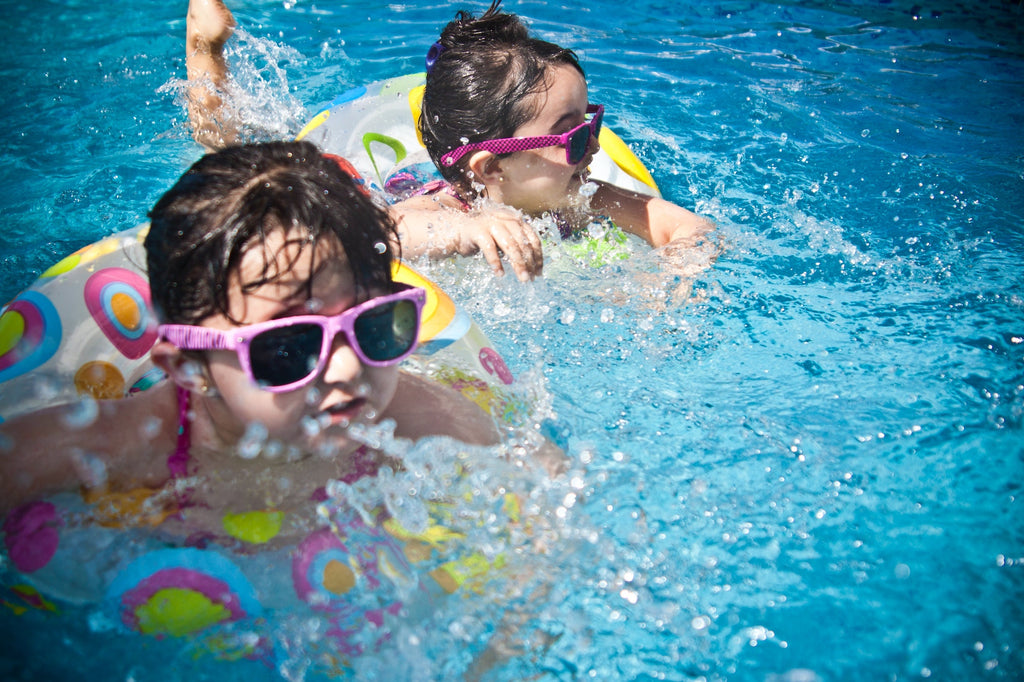 two young girls swimming in pool with floating toys